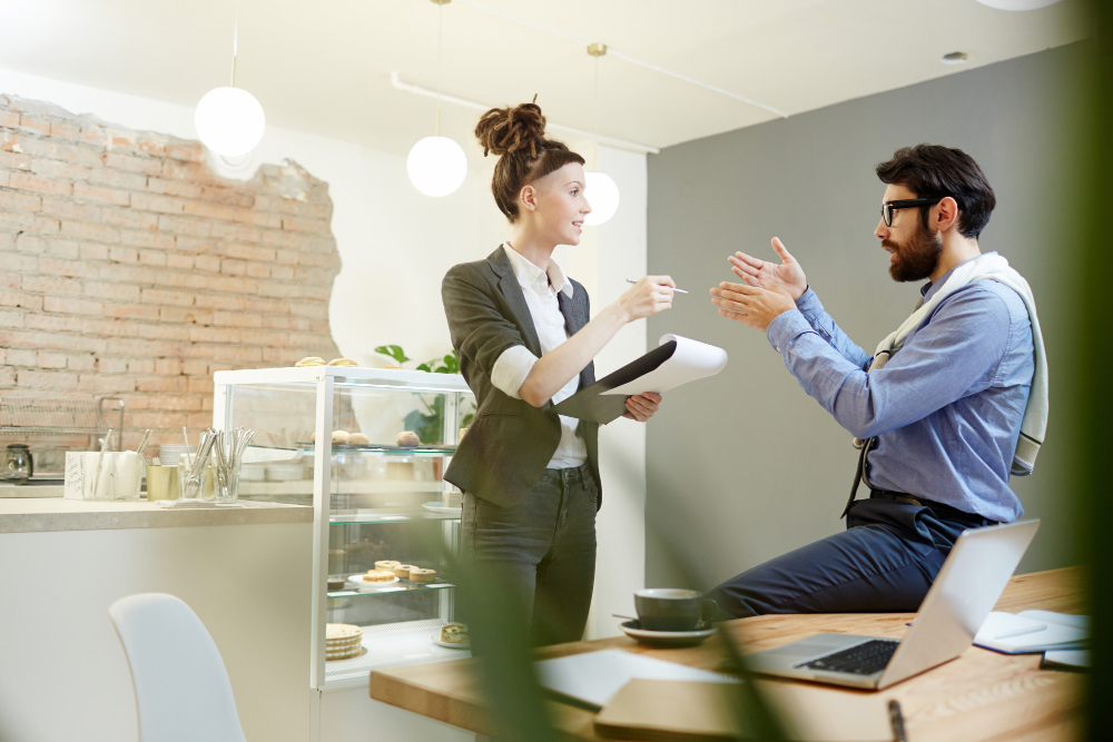 Persona escribiendo en un portátil con notas y un checklist, representando redacción profesional, claridad y persuasión en la comunicación empresarial.