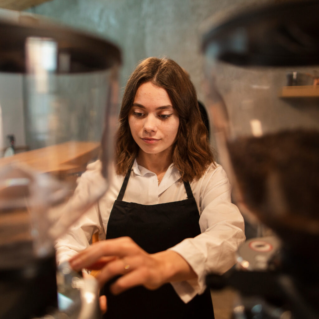 Personal de hostelería atendiendo en un restaurante, con bandeja y ambiente de sala, representando formación y servicio al cliente.